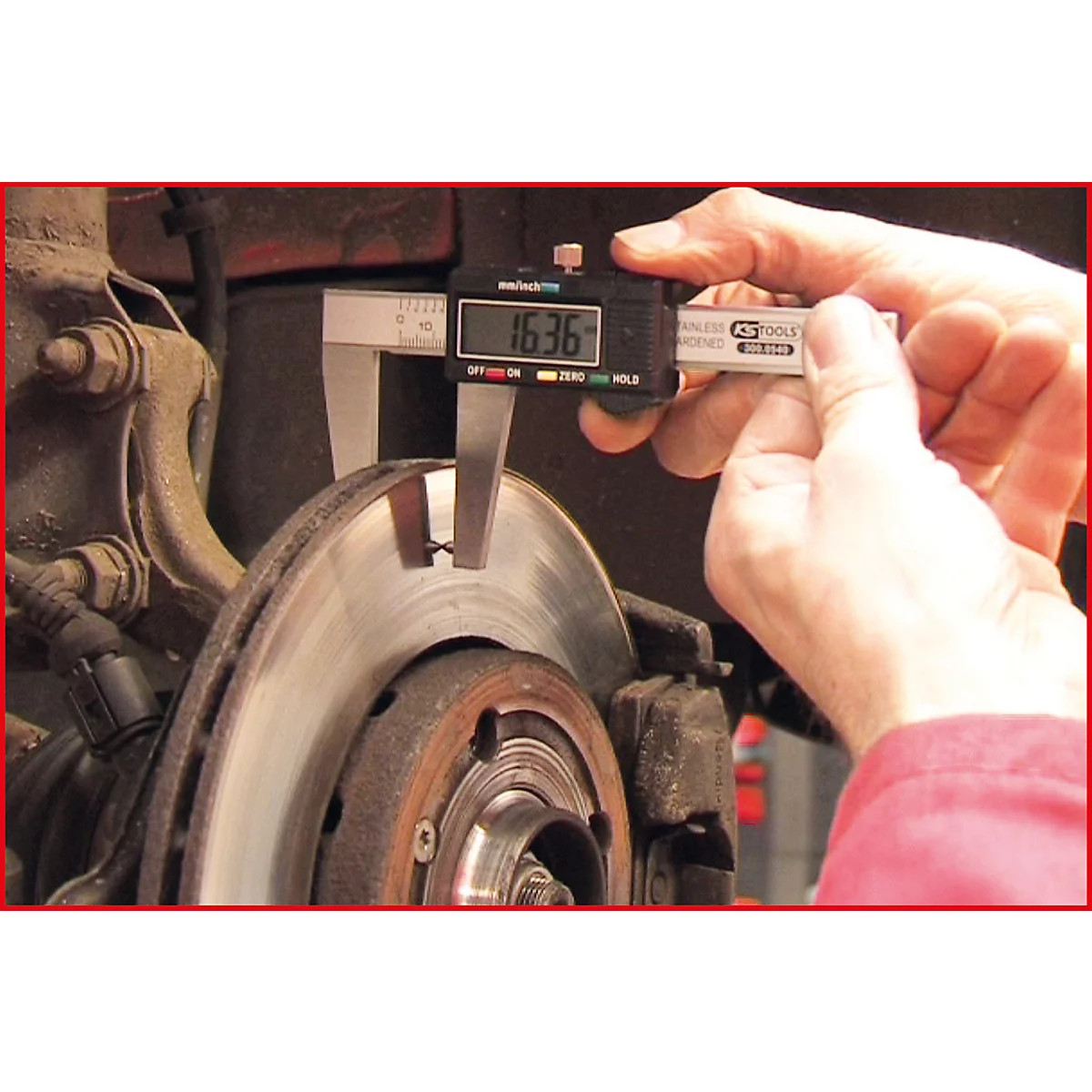 Eine Person misst mit einem digitalen Messschieber die Dicke einer Bremsscheibe, Anzeige 16,36.